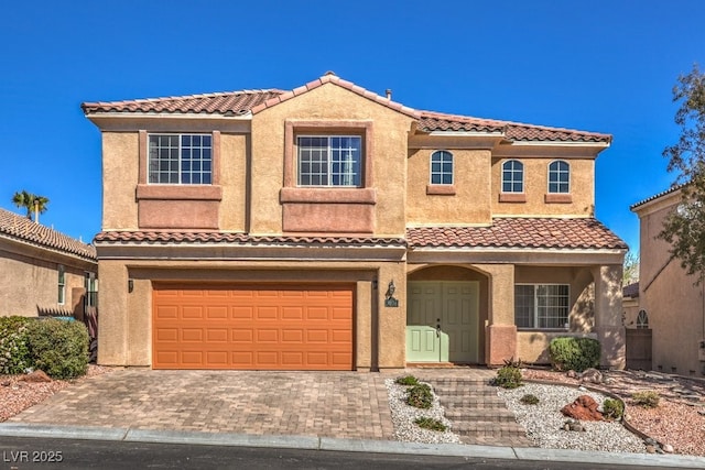 view of front of property featuring a garage, decorative driveway, a tile roof, and stucco siding