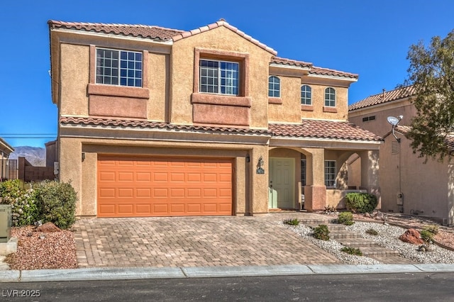 view of front of home with a garage, decorative driveway, a tiled roof, and stucco siding