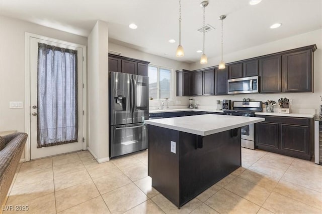 kitchen featuring light tile patterned flooring, appliances with stainless steel finishes, decorative light fixtures, a center island, and dark brown cabinets