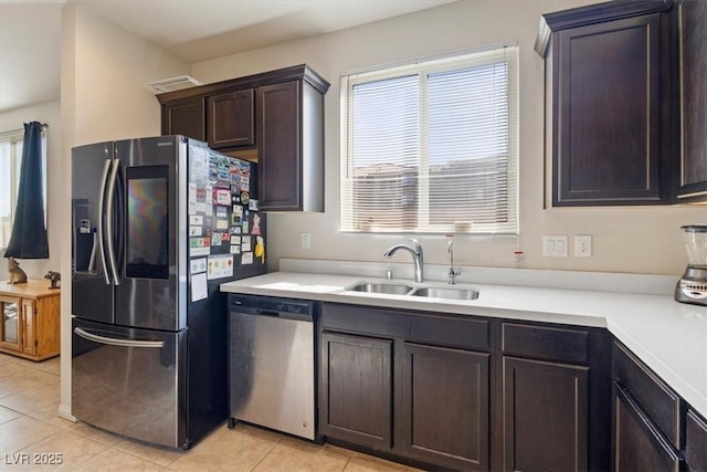 kitchen featuring dark brown cabinetry, sink, light tile patterned floors, and stainless steel appliances