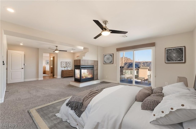 bedroom featuring light colored carpet, access to exterior, and a tiled fireplace