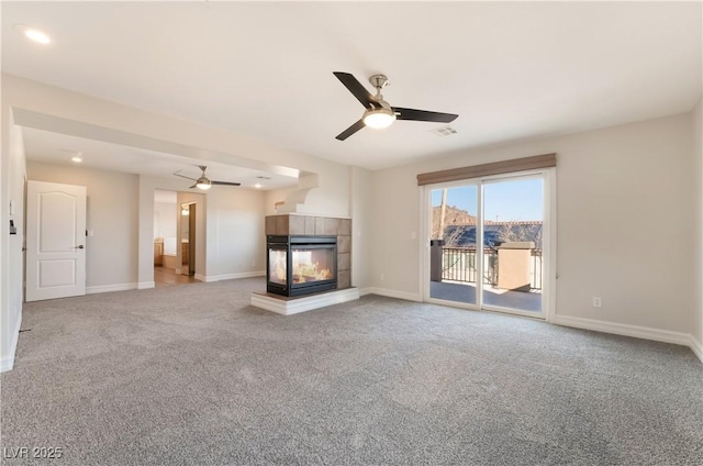 unfurnished living room with a multi sided fireplace, carpet flooring, and ceiling fan