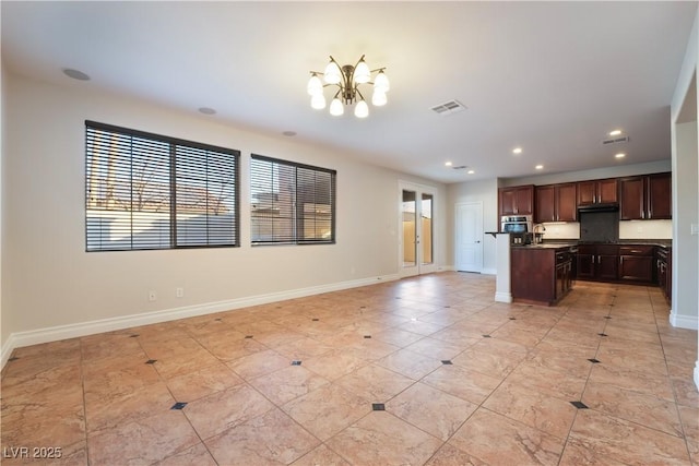 kitchen with sink, oven, dark brown cabinets, a center island with sink, and an inviting chandelier