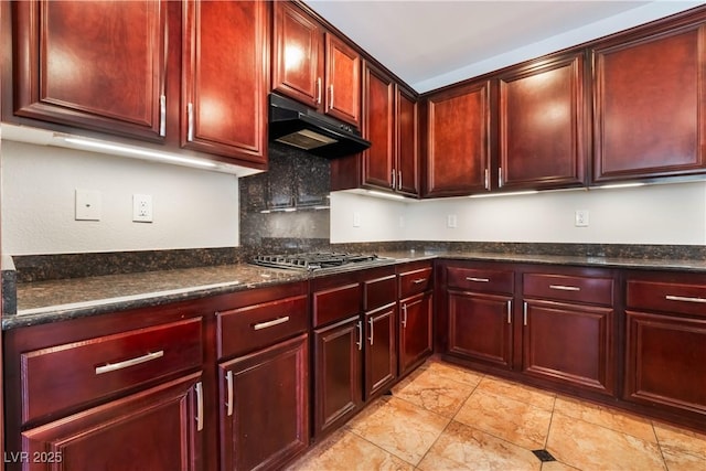 kitchen with tasteful backsplash, dark stone counters, and stainless steel gas stovetop