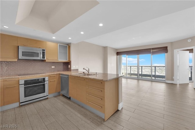 kitchen featuring appliances with stainless steel finishes, sink, decorative backsplash, and kitchen peninsula