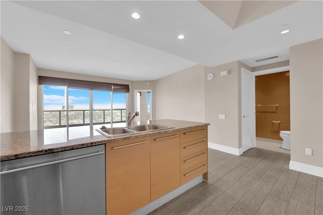 kitchen with sink, dishwasher, stone counters, light hardwood / wood-style floors, and light brown cabinetry