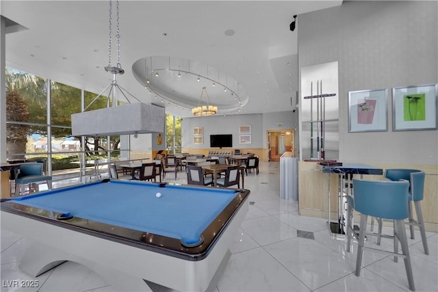 recreation room with a raised ceiling, a high ceiling, and a chandelier