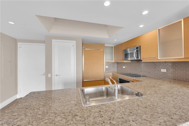 kitchen featuring sink, paneled built in fridge, black electric cooktop, decorative backsplash, and a raised ceiling