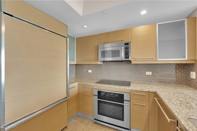 kitchen with light stone counters, stainless steel appliances, light hardwood / wood-style floors, and decorative backsplash