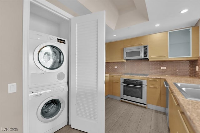 laundry area featuring sink, light hardwood / wood-style floors, and stacked washer and clothes dryer