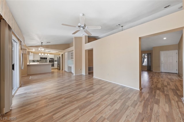 unfurnished living room featuring lofted ceiling, ceiling fan with notable chandelier, and light hardwood / wood-style flooring