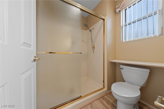 bathroom featuring hardwood / wood-style flooring, toilet, and a shower with shower door