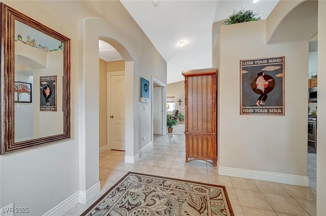 corridor featuring vaulted ceiling and light tile patterned floors