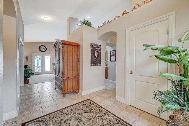 hall with a high ceiling, light tile patterned flooring, and french doors