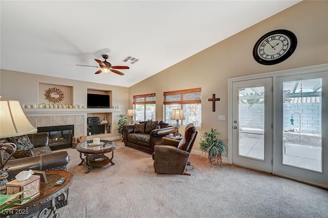 living room with a tiled fireplace, lofted ceiling, ceiling fan, and carpet flooring