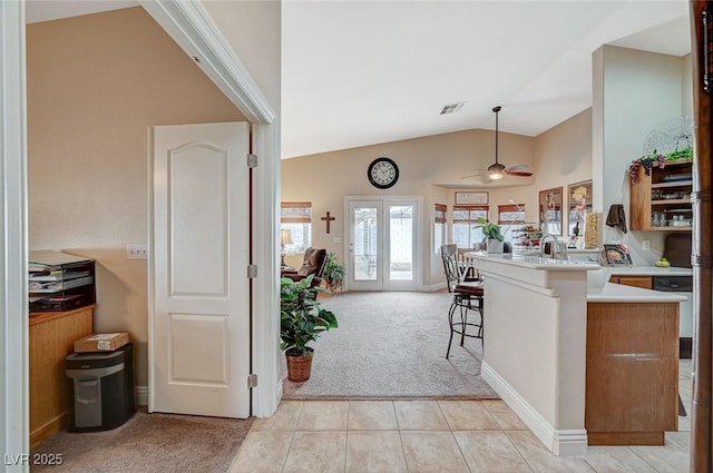 kitchen with french doors, a breakfast bar area, vaulted ceiling, light carpet, and kitchen peninsula