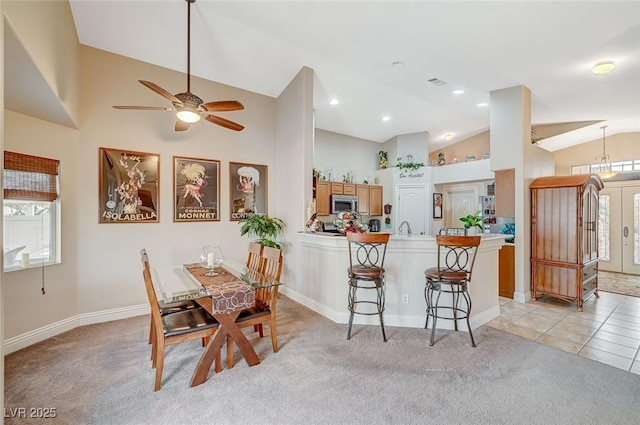 dining area with high vaulted ceiling and light colored carpet