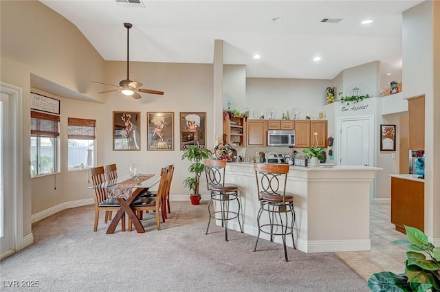 kitchen with a breakfast bar area, light colored carpet, and a towering ceiling