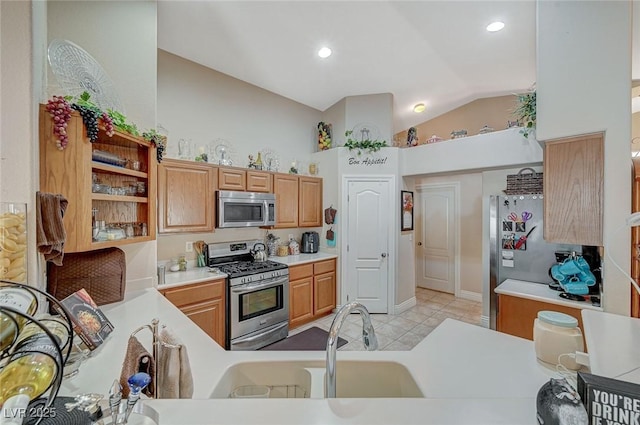 kitchen with vaulted ceiling, appliances with stainless steel finishes, sink, and light tile patterned floors