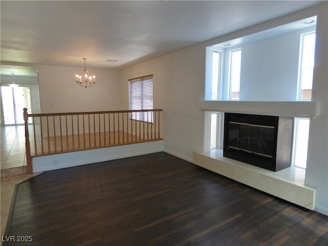 unfurnished living room with a healthy amount of sunlight, dark hardwood / wood-style floors, and a chandelier