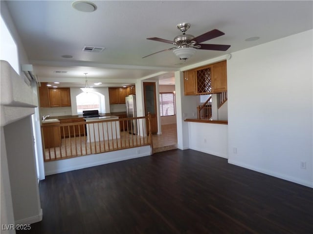 unfurnished living room with sink, dark wood-type flooring, and ceiling fan