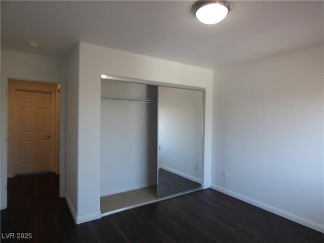 unfurnished bedroom with dark hardwood / wood-style flooring and a closet