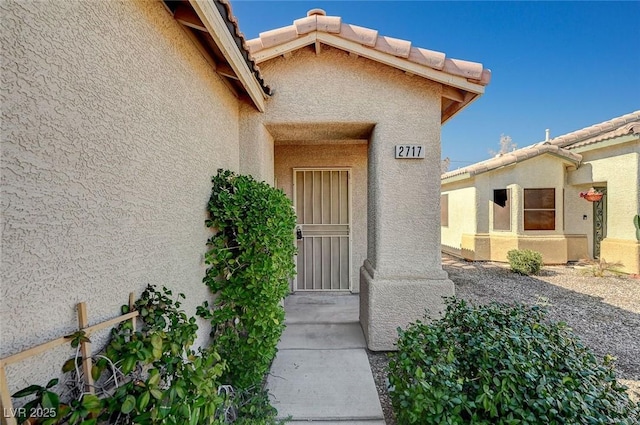 doorway to property with a tiled roof and stucco siding