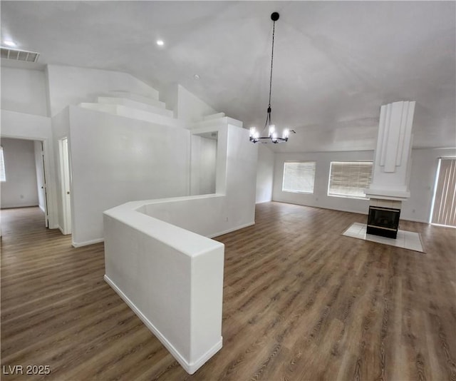 unfurnished living room featuring dark wood-type flooring, lofted ceiling, and a notable chandelier