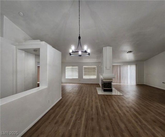 unfurnished living room featuring an inviting chandelier, a multi sided fireplace, and dark hardwood / wood-style flooring