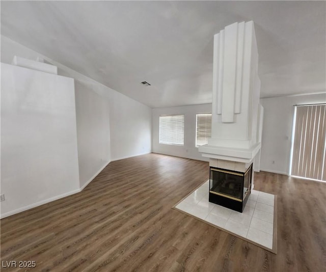 unfurnished living room with hardwood / wood-style flooring and a tiled fireplace