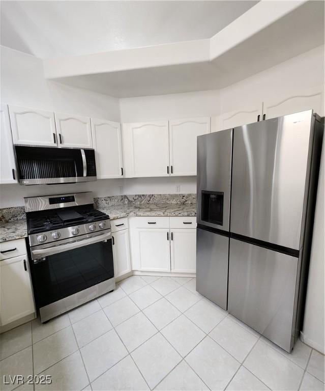 kitchen featuring light stone countertops, white cabinetry, appliances with stainless steel finishes, and light tile patterned floors