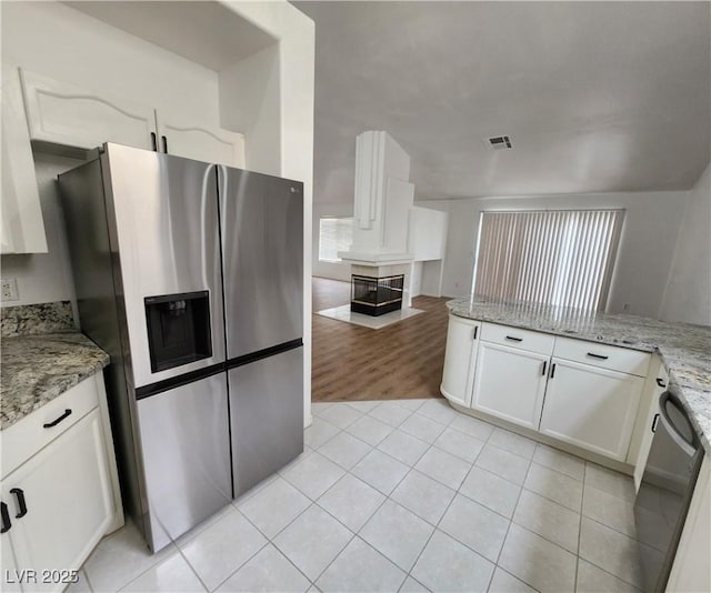 kitchen with dishwasher, white cabinets, light stone counters, and stainless steel fridge with ice dispenser