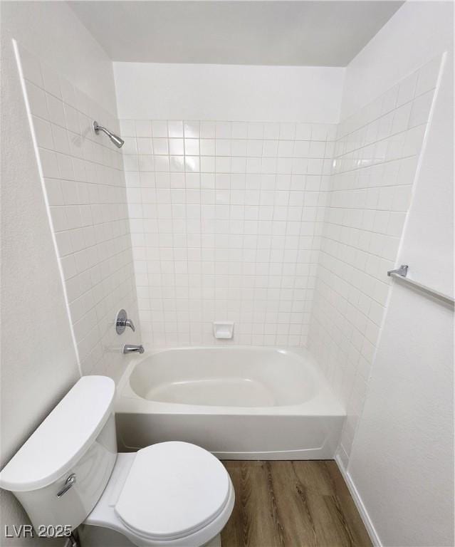 bathroom with wood-type flooring, toilet, and tiled shower / bath combo