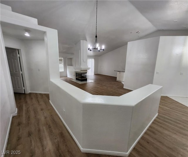 unfurnished living room with dark hardwood / wood-style floors, a chandelier, and vaulted ceiling