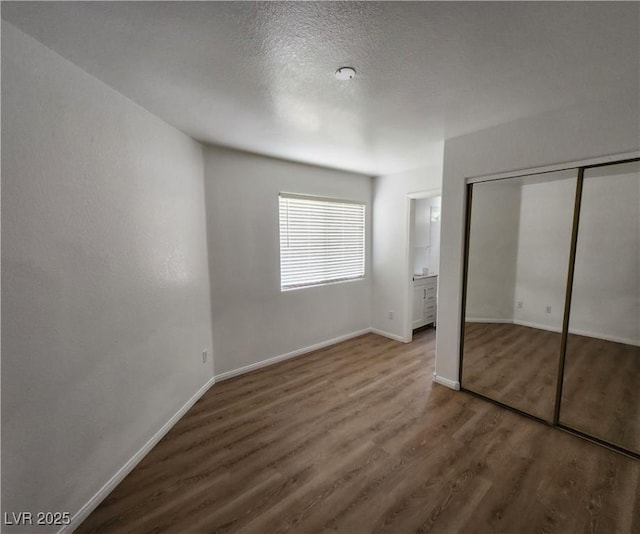 unfurnished bedroom with wood-type flooring, a closet, and a textured ceiling