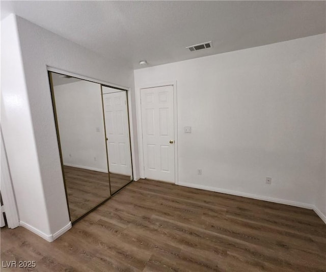 unfurnished bedroom with dark wood-type flooring and a closet