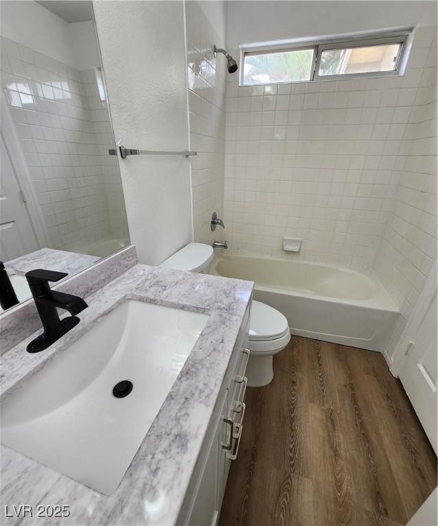 full bathroom featuring hardwood / wood-style flooring, vanity, toilet, and tiled shower / bath combo