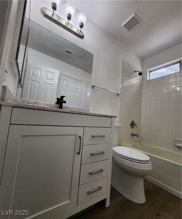 full bathroom with vanity, wood-type flooring, toilet, and tiled shower / bath