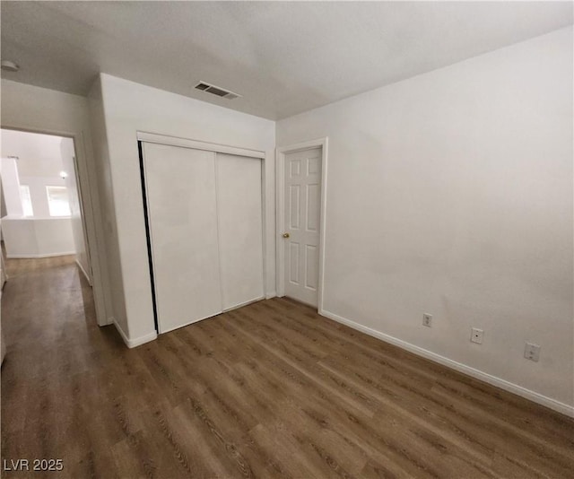 unfurnished bedroom with dark hardwood / wood-style floors and a closet