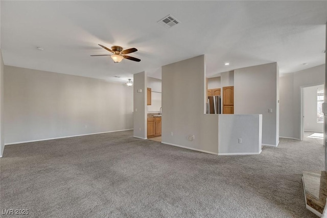 unfurnished living room featuring sink, light colored carpet, and ceiling fan