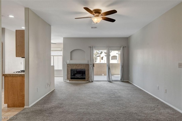 unfurnished living room featuring ceiling fan, light colored carpet, and plenty of natural light