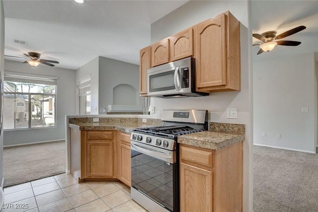 kitchen featuring stainless steel appliances, ceiling fan, light colored carpet, and light brown cabinets