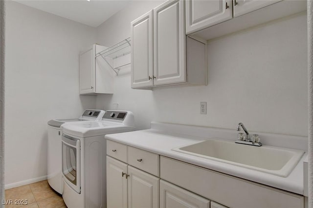 clothes washing area featuring sink, light tile patterned floors, cabinets, and washer and dryer