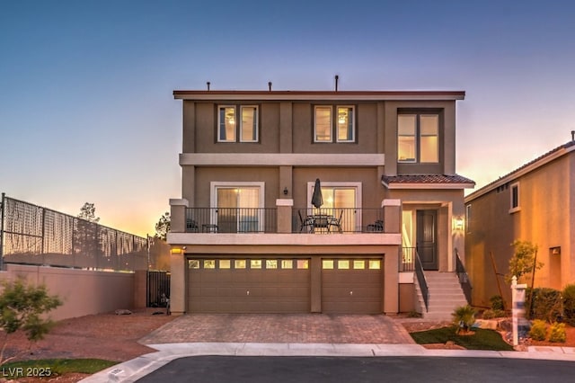 view of front of property with stucco siding, decorative driveway, a garage, and fence