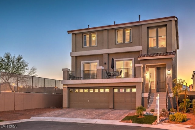 view of front of property with fence, stucco siding, decorative driveway, a balcony, and a garage