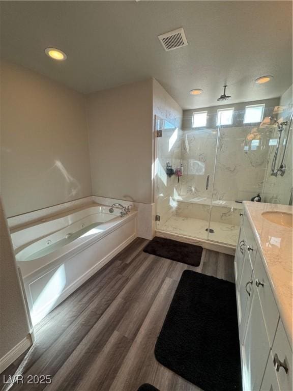 full bathroom with a marble finish shower, visible vents, wood finished floors, a bath, and vanity