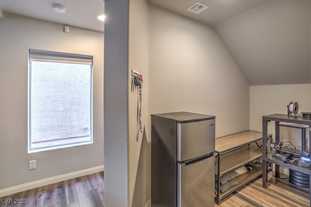 interior space featuring lofted ceiling, wood finished floors, visible vents, and baseboards