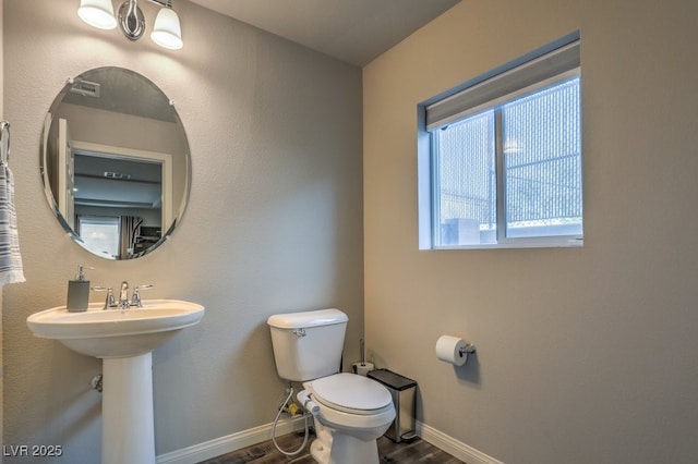 bathroom featuring toilet, wood finished floors, baseboards, and a sink