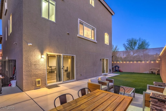 rear view of property with a patio area, stucco siding, fence private yard, and a yard