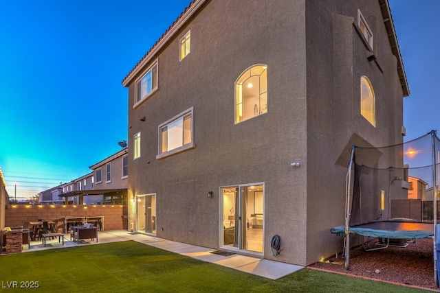 back of property featuring stucco siding, a patio, and a trampoline